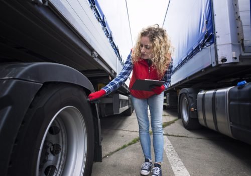 Truck driver checking vehicle tires and inspecting truck before ride.